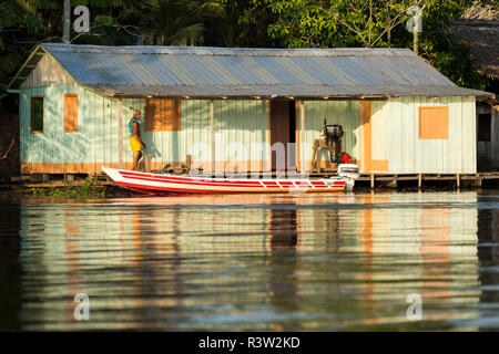 Man walks in warm light on his front porch dock at a river house along the Amazon River, Brazil Stock Photo