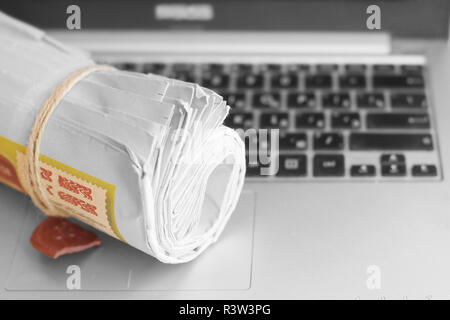 Newspapers and computer. Folded and rolled papers and magazines on keyboard of open laptop. Concept for news by different sources of information Stock Photo