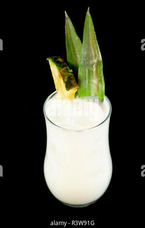 Pina Colada cocktail with pineapple juice, white rum and coconut cream decorated with pineapple fruit and leaf with isolated black background Stock Photo