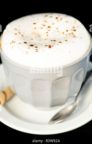 Delicious Cappuccino served with chocolate hazelnut wafer roll isolated black background Stock Photo