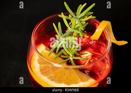 Gotfather cocktail with bourbon whiskey, amaretto, orange wedge and rosemary with isolated black background Stock Photo