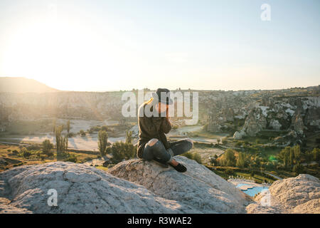 The girl sits on top of a hill, covers her face with her hands and cries. She is upset and sad. Stock Photo