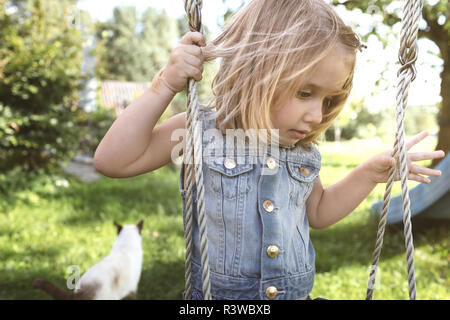 Little girl sitting on swing in the garden Stock Photo