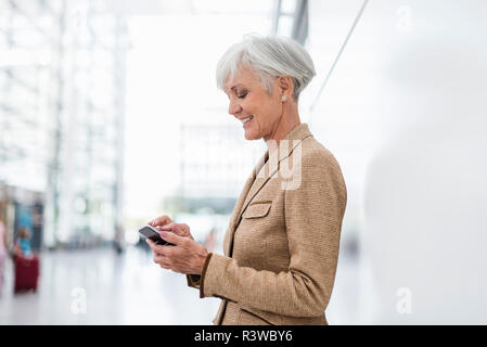 Smiling senior businesswoman using cell phone Stock Photo