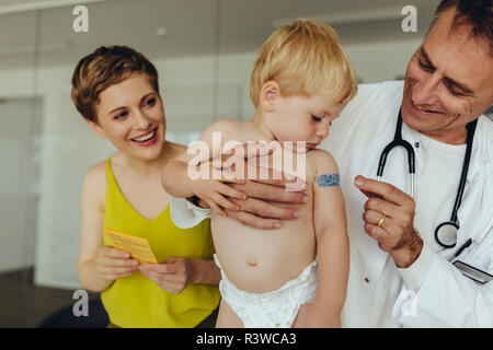 Doctor putting band aid on toddler's arm after vaccination Stock Photo