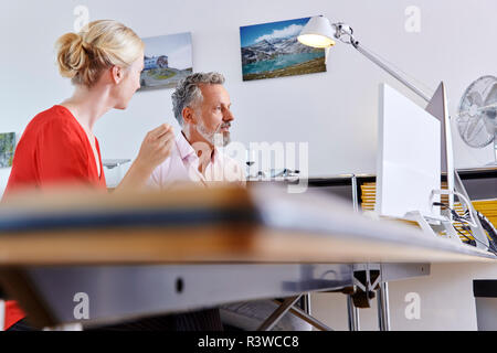 Two colleagues working together at desk in office Stock Photo