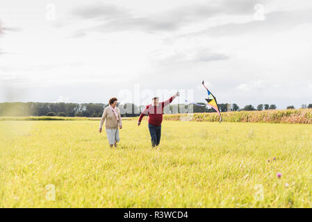 Happy senior couple flying kite in rural landscape Stock Photo