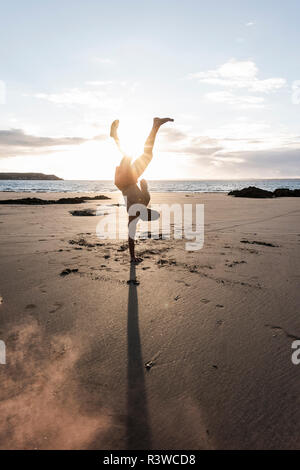 Man doing movement training at the beach at sunset Stock Photo