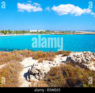 Image of a bay near Nissi beach, Agia Napa, Cyprus. Rough limestone coastline near deep blue transparent azure water with white clouds in the sky on t Stock Photo
