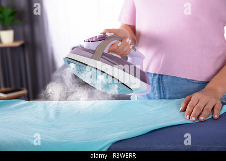 Close-up Of A Woman's Hand Ironing Cloth With Electric Iron Stock Photo