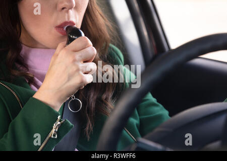 Side View Of A Beautiful Young Woman Sitting Inside Car Taking Alcohol Test Stock Photo