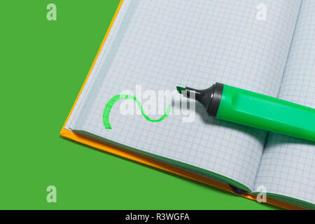 opened copybook and a marker on a green surface Stock Photo