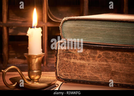 Old book on wooden table by candlelight Stock Photo