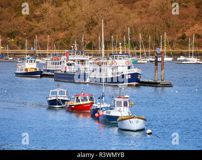 Small motor boats on trot moorings and larger passenger ferries moored to a pontoon in Dartmouth Harbour during early springtime Stock Photo