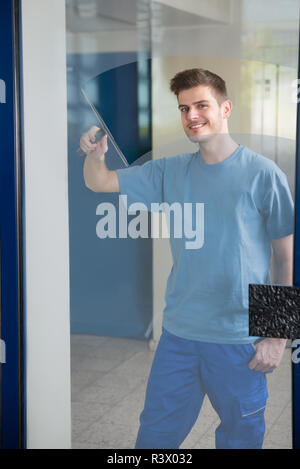 Worker Cleaning Glass With Squeegee Stock Photo