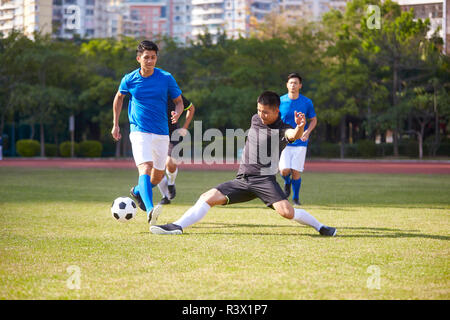 a group of young asian soccer football player playing on outdoor court. Stock Photo