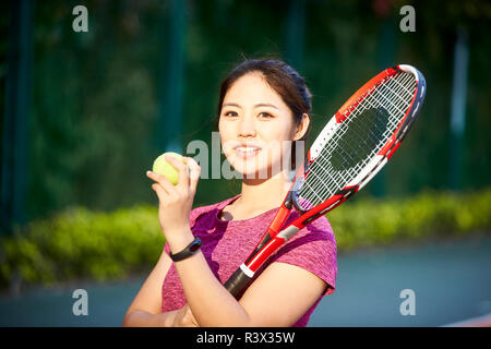 outdoor portrait of a young asian tennis player looking at camera smiling Stock Photo