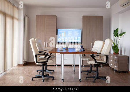 Empty conference room in business center. There is a TV displaying some graphs and charts on the background Stock Photo