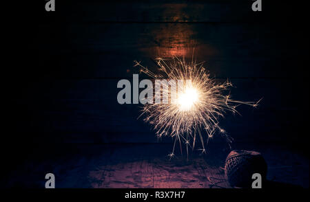 burning sparkler and christmas lights on wooden background Stock Photo