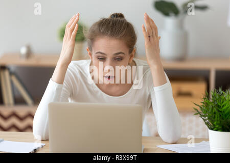 Frustrated girl reading shocking news at laptop Stock Photo