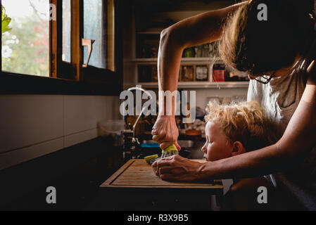 Mother helped her son to squeeze fruit. Stock Photo