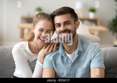 Portrait of happy millennial couple hug on couch at home Stock Photo