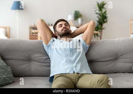 Calm man relaxing on sofa hands over head Stock Photo