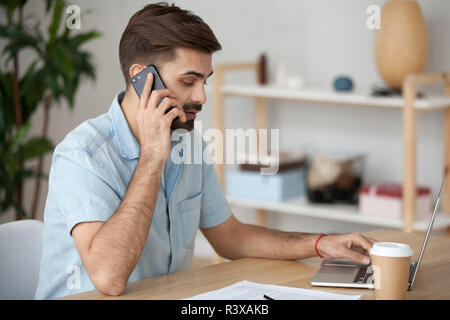 Busy man talking on cell working using laptop  Stock Photo