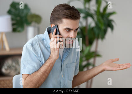 Angry man talking on smartphone solving work problem Stock Photo