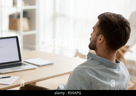 Back view of tired male falling asleep at workplace Stock Photo