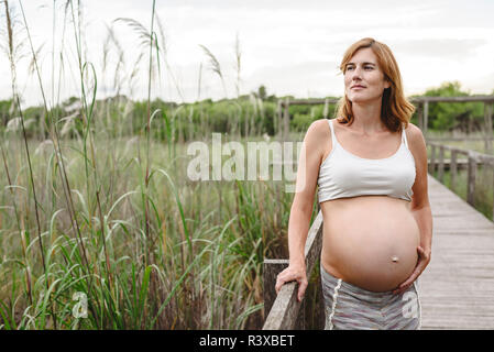 Pregnant woman walking among trees and nature. Stock Photo