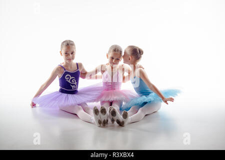 Three little ballet girls sitting in tutu and posing together Stock Photo