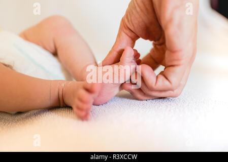 Mommy grabbing the little feet of her newborn daughter. Stock Photo