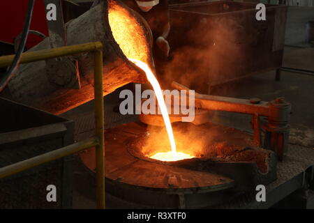 Molten iron pour from ladle into melting furnace ; foundry porcess Stock Photo