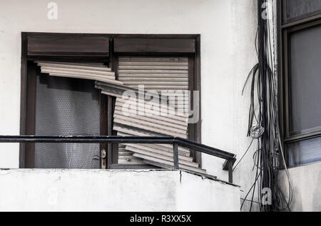 Broken blinds/shutters and telephone cables on old apartment block. Stock Photo