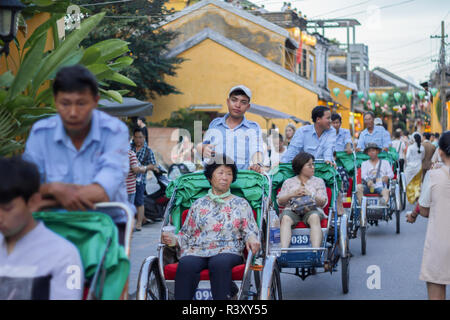 cycle rickshaws riding tourists around Hoi An Ancient Town. Stock Photo