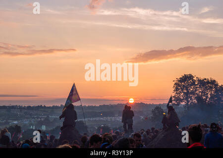 Glastonbury Festival. 30th June. 2014. A crowd watching the sunrise at Glastonbury Festival. With a couple watching the sunrise Stock Photo