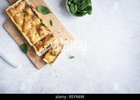 Salmon Spinach Pie (quiche) with cheese on white background. Homemade salmon tart for healthy lunch, top view, copy space. Stock Photo