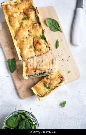 Salmon Spinach Pie (quiche) with cheese on white background. Homemade salmon tart for healthy lunch, top view, copy space. Stock Photo