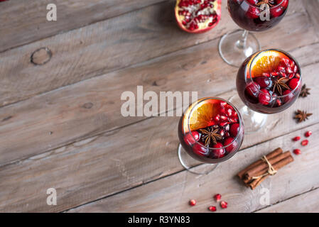 Red Sangria with oranges, pomegranate seeds, cranberry, rosemary and spices - homemade festive autumn or winter drink mulled wine, sangria. Stock Photo