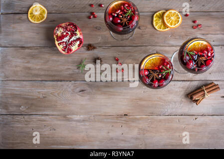Red Sangria with oranges, pomegranate seeds, cranberry, rosemary and spices - homemade festive autumn or winter drink mulled wine, sangria. Stock Photo