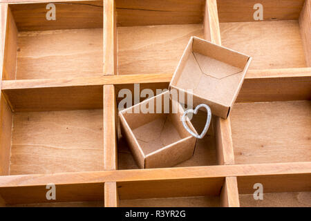 Open cardboard box inside a wooden box with compartments and a heart Stock Photo