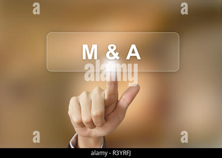 business hand clicking merger and acquisition button on blurred background Stock Photo