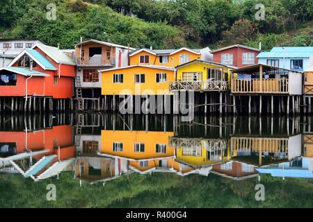 Colorful stilt houses, pile dwellings, called palafitos, with water reflection, Castro, island Chiloé, Chile Stock Photo