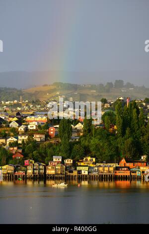 Rainbow over the city with stilt houses, called palafitos, in the morning light, Castro, island Chiloé, Chile Stock Photo