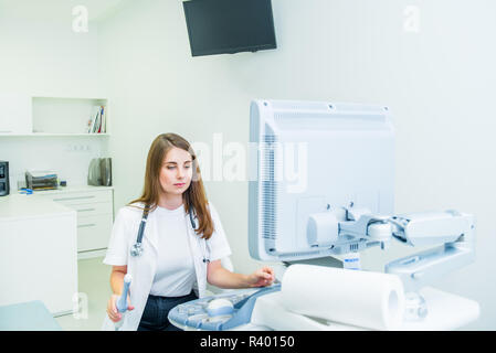Serious, concentrated young doctor, specialist using Ultrasound Scanning Machine for pacient testing. Copy space. Selective focus Stock Photo