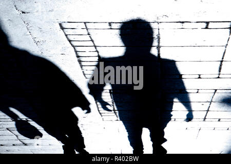 Blurry silhouette and shadow of two people walking the city street in the night Stock Photo