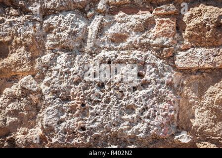 Horizontal photo with texture of ancient wall. Wall is built from stones and bricks. Bricks are orange and brown and significantly worn. Stones are ve Stock Photo