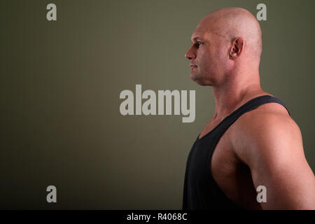 Bald muscular man wearing tank top against colored background  Stock Photo