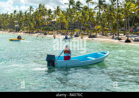 The rescue boat and the people relaxing on the beach among palm trees in the resort of Punta Cana.